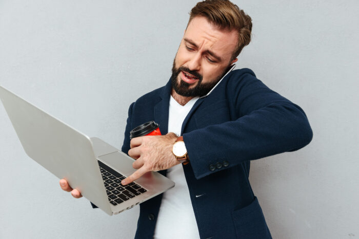 Busy bearded man in business clothes talking by smartphone