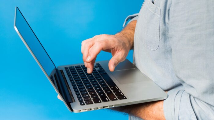 Closeup of man holding laptop illustrates blog: "Cybersecurity Tips for Small Businesses"