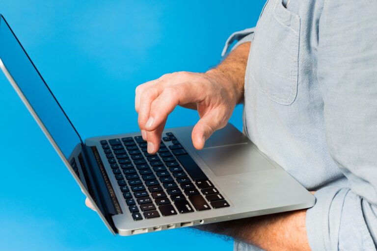 Closeup of man holding laptop illustrates blog: "Cybersecurity Tips for Small Businesses"