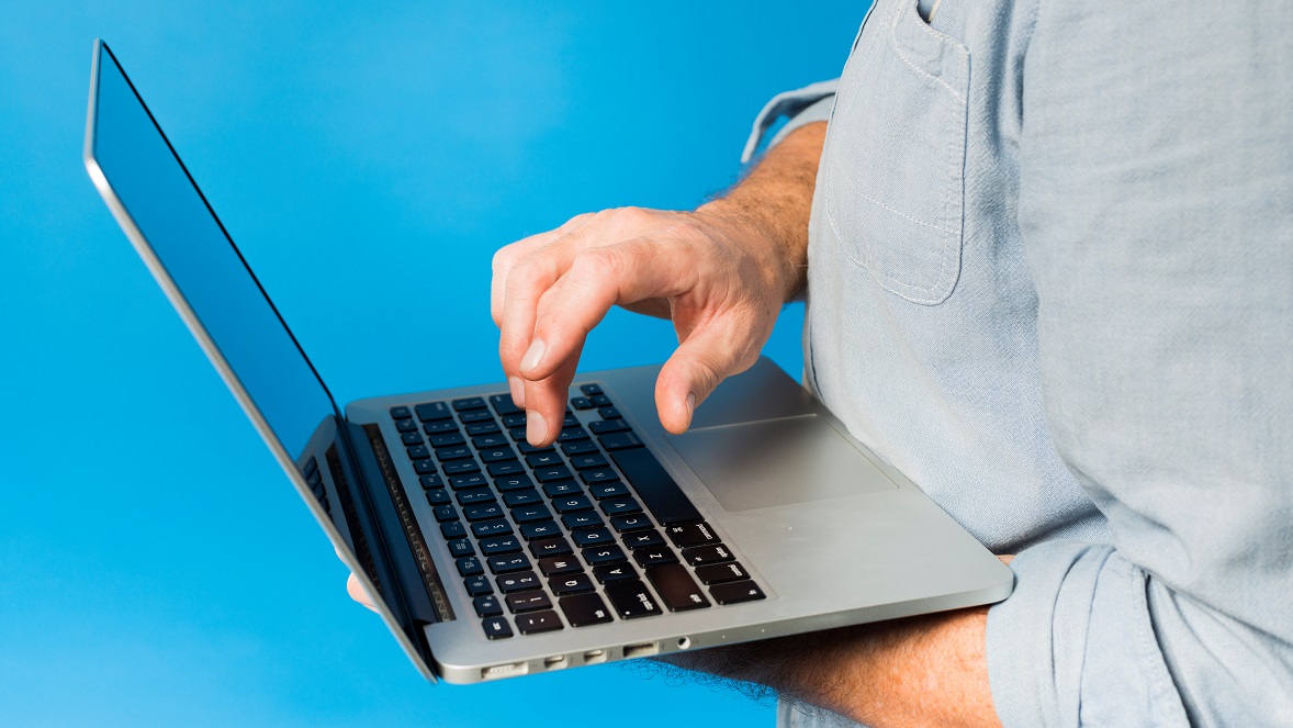Closeup of man holding laptop illustrates blog: "Cybersecurity Tips for Small Businesses"