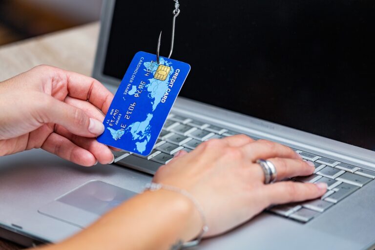 Photo of person holding credit card pierced by a fish hook illustrates blog: "Here's How to Deal With Phishing Emails"