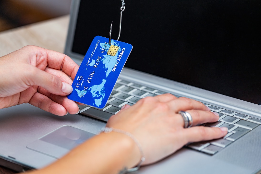 Photo of person holding credit card pierced by a fish hook illustrates blog: "Here's How to Deal With Phishing Emails"