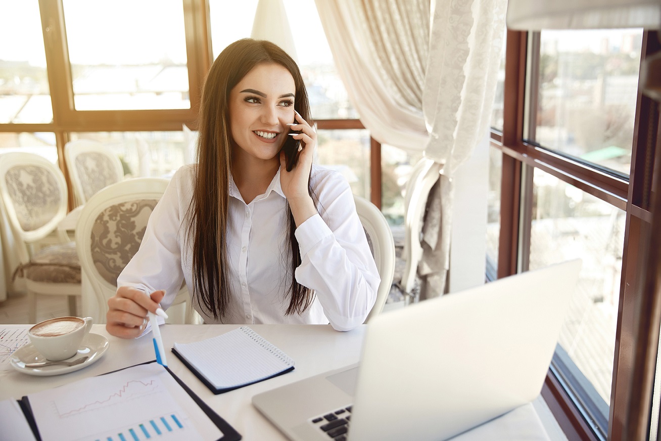 Photo of smiling woman talking on the phone illustrates blog: "4 Basic Customer Service Skills (and How to Develop Them)"