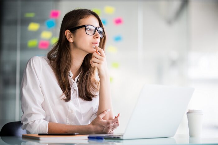 Photo of woman thinking in office illustrates blog "The Importance of Critical Thinking in the Workplace"