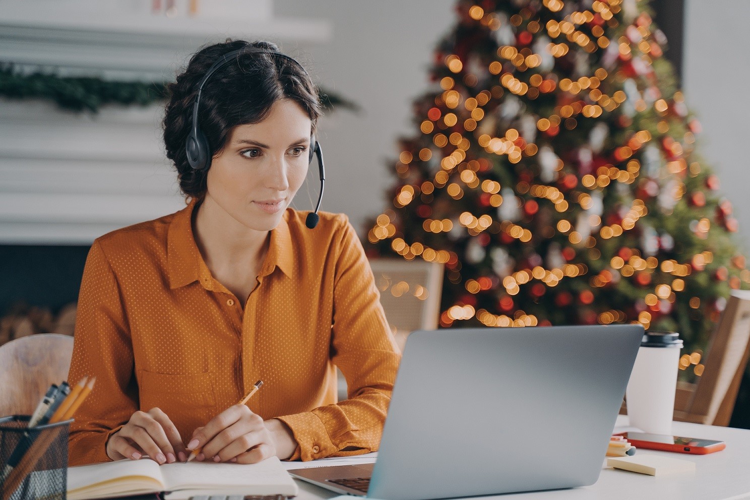 Photo of worker with headset and Christmas tree behind her.