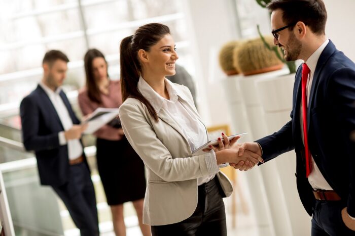 Photo of businesswoman and businessman shaking hands illustrates blog: "9 Entrepreneurship Quotes to Give You the Motivation and Wisdom You Need"