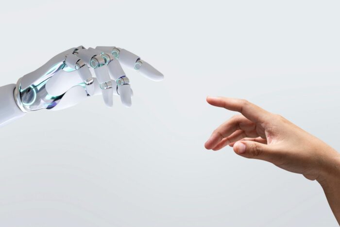 Photo of human hand touching fingers with robot hands.