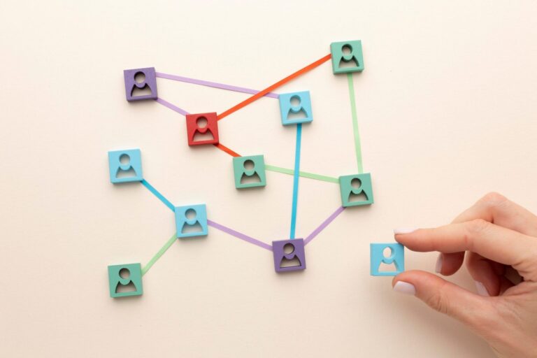 Close-up of hand arranging pieces with icons of people united by strings illustrates blog "Get Your Networking Skills to the Next Level"