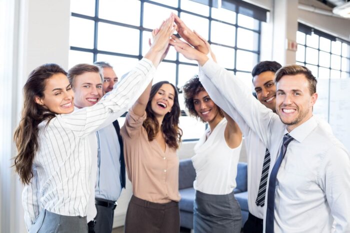 Group of smiling employees illustrate blog: "Keeping Employees Happy and Productive: How to Reduce Employee Turnover"