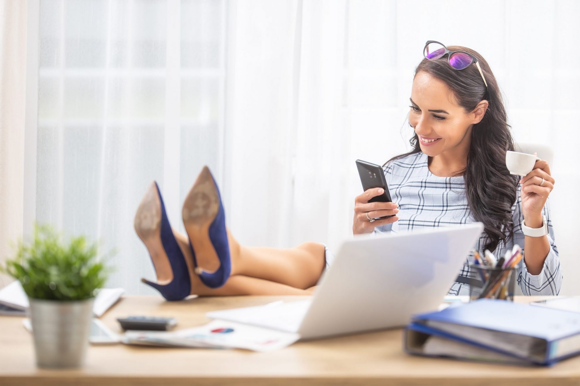 Smiling woman with feet on desk illustrates blog "5 Ideas for Breaking Free from Procrastination"