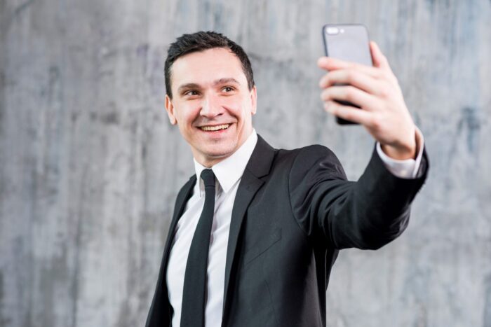 Businessman taking selfie illustrates blog "5 Ideas to Build Your Brand"