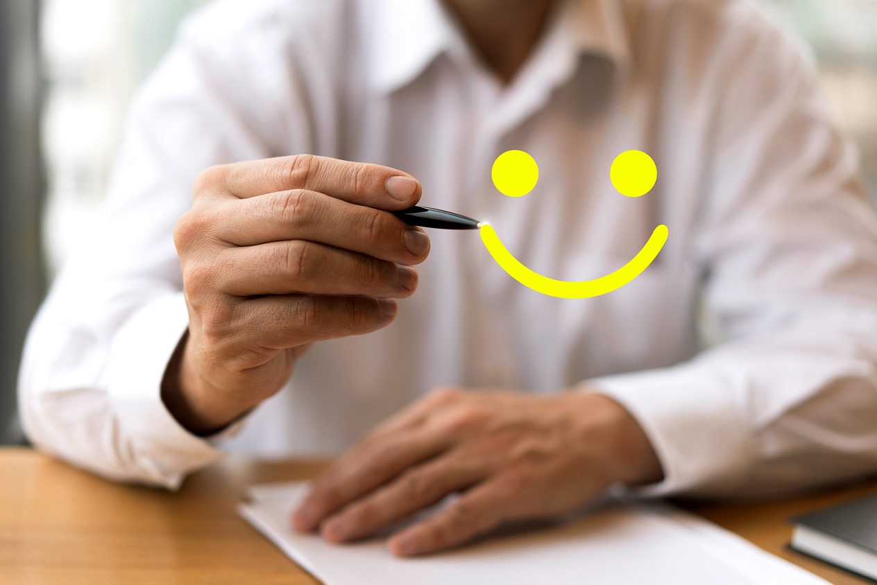CustomerHappy2 Man with pen drawing a yellow smiley face in the air in front of him.