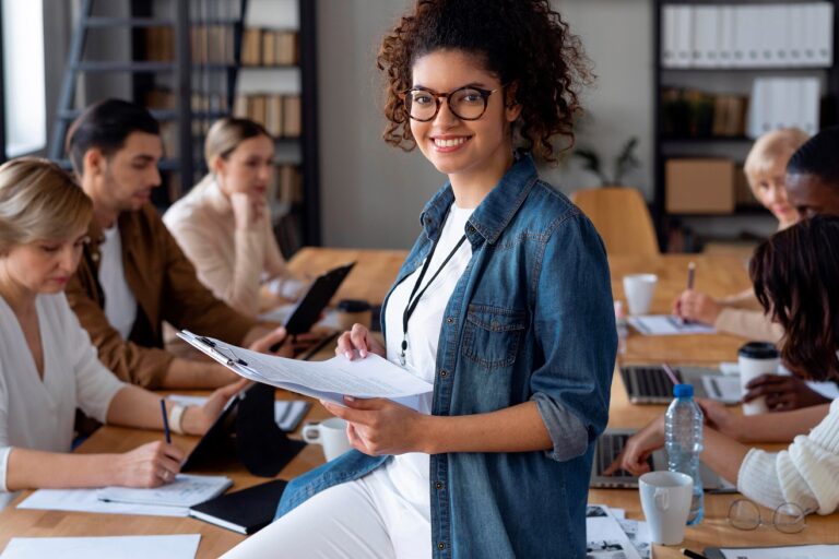 Smiling woman in meeting room illustrates blog "5 Tips To Be More Organized"
