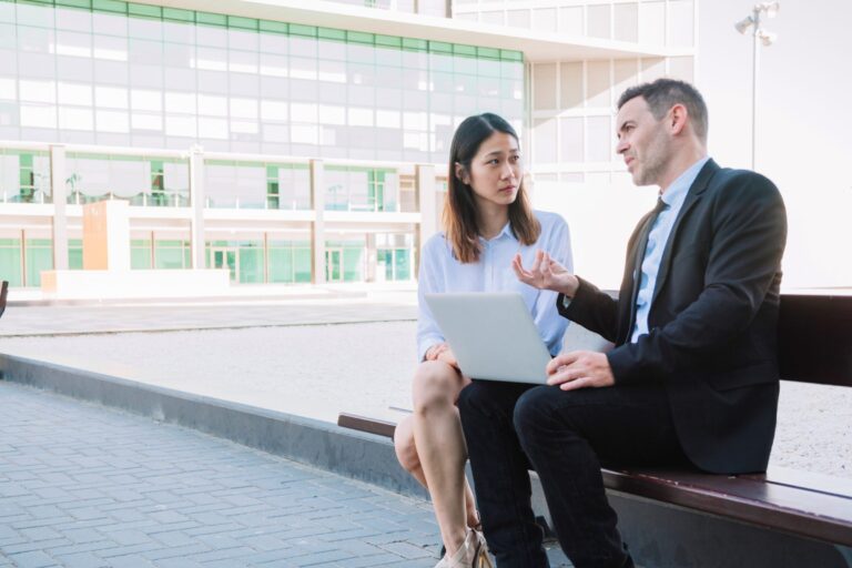 Man and woman in business attire talking outdoors illustrate blog "What Is Active Listening?"