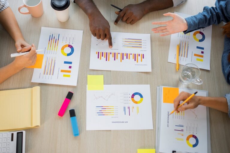 Photo of people at table pointing at graphics/