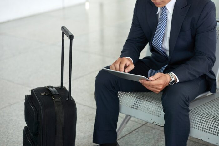 Business traveler holding tablet with trolley by his side.