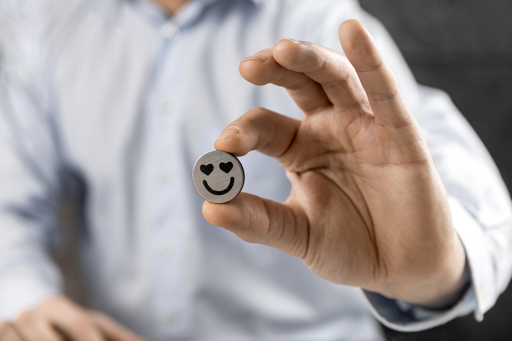customer-satsfaction-freepik Man holding small smiley face with heart eyes.