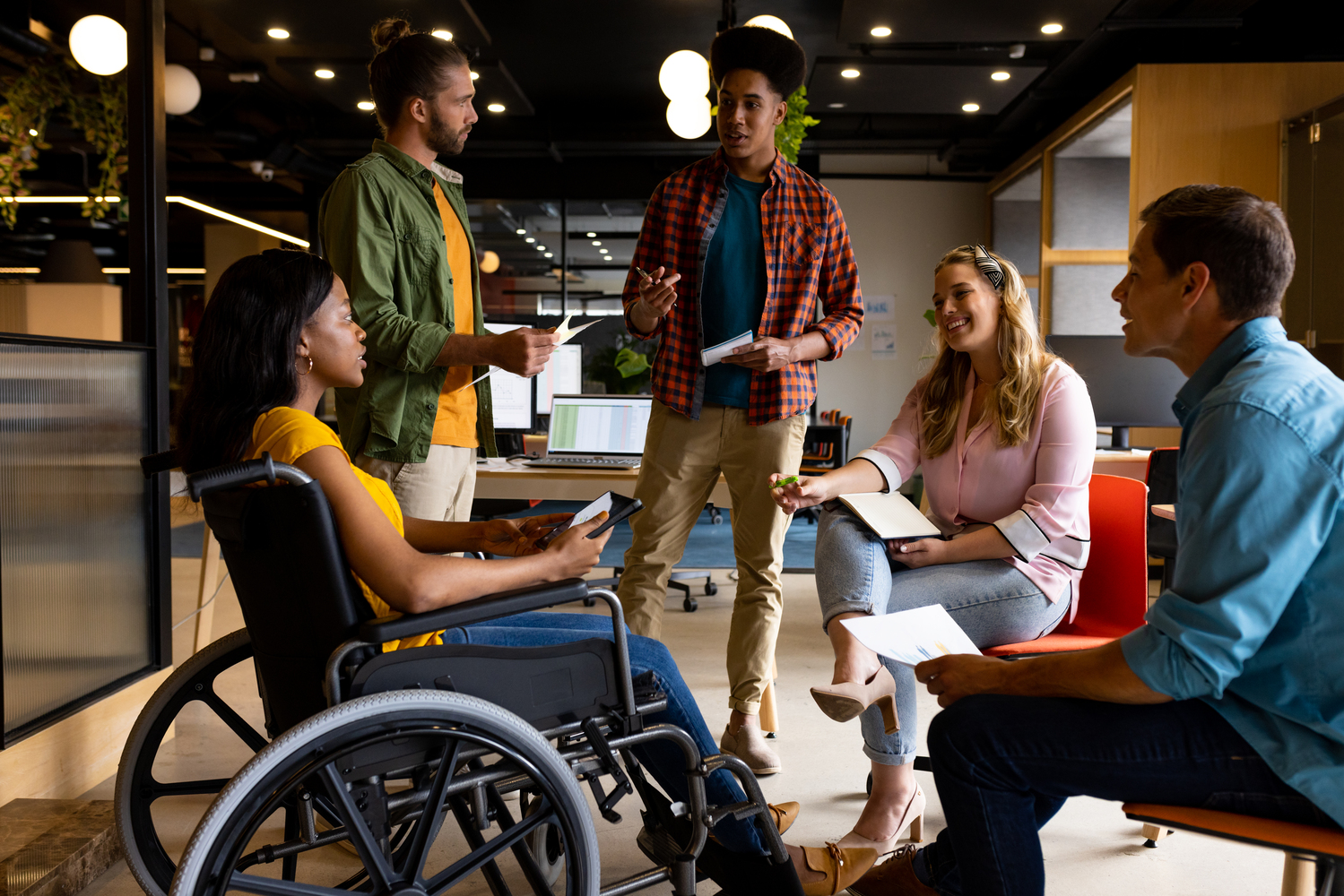 Diverse male and female colleagues in discussion in casual office meeting. Casual office, teamwork, disability, inclusivity, business and work, unaltered.